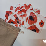 Lot de sept carrés démaquillants lavables au motif coquelicots rouges sur fond blanc, disposés en éventail à côté de leur pochon en lin beige Cocon Couture.