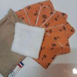 Lot de sept carrés démaquillants lavables Cocon Couture au motif fleurs printanières orange, disposés en éventail avec un carré retourné sur le côté éponge blanc, à côté de leur pochon en lin beige.