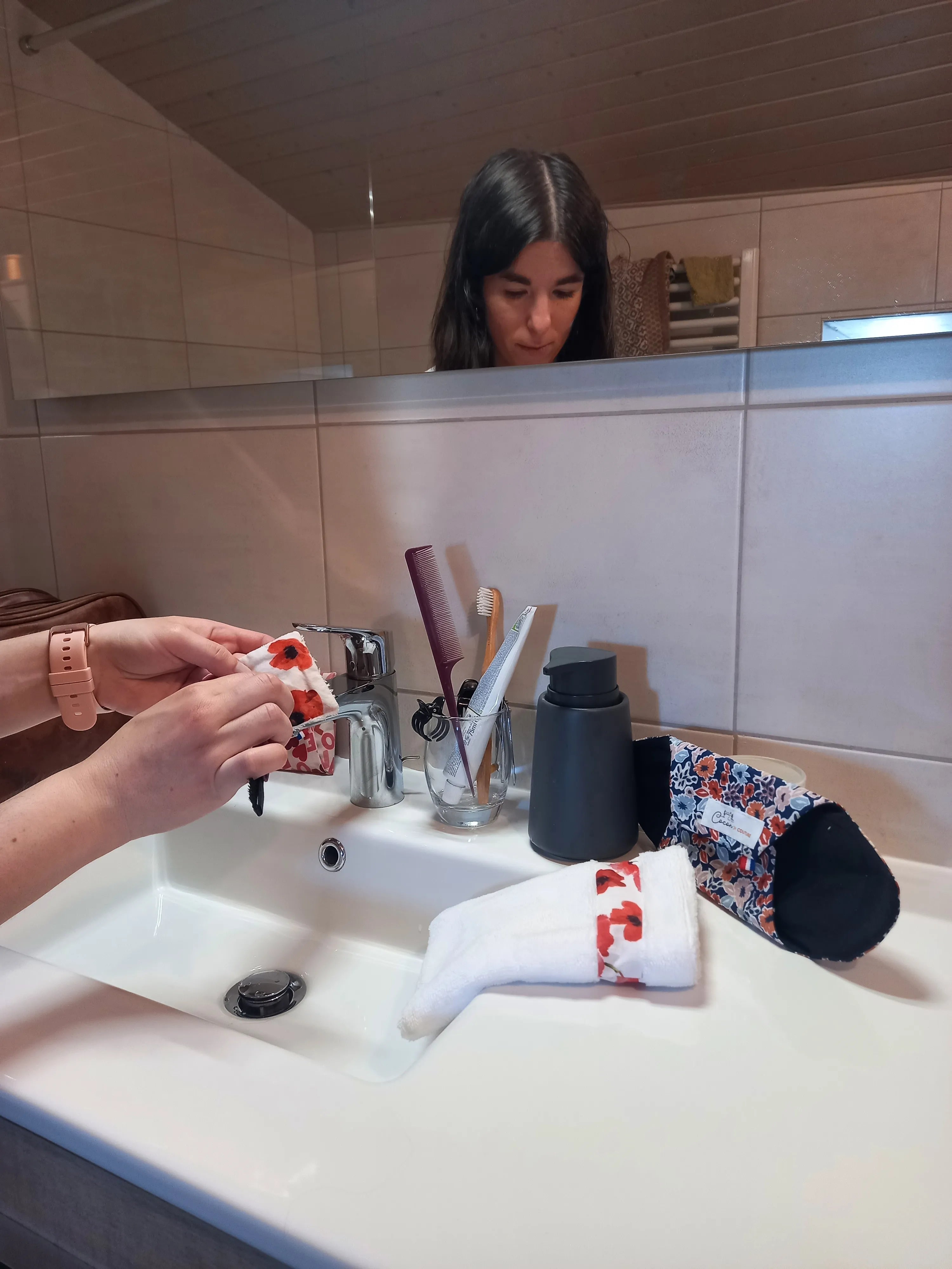 Une personne nettoie un carré de coton démaquillant lavable dans une salle de bain.