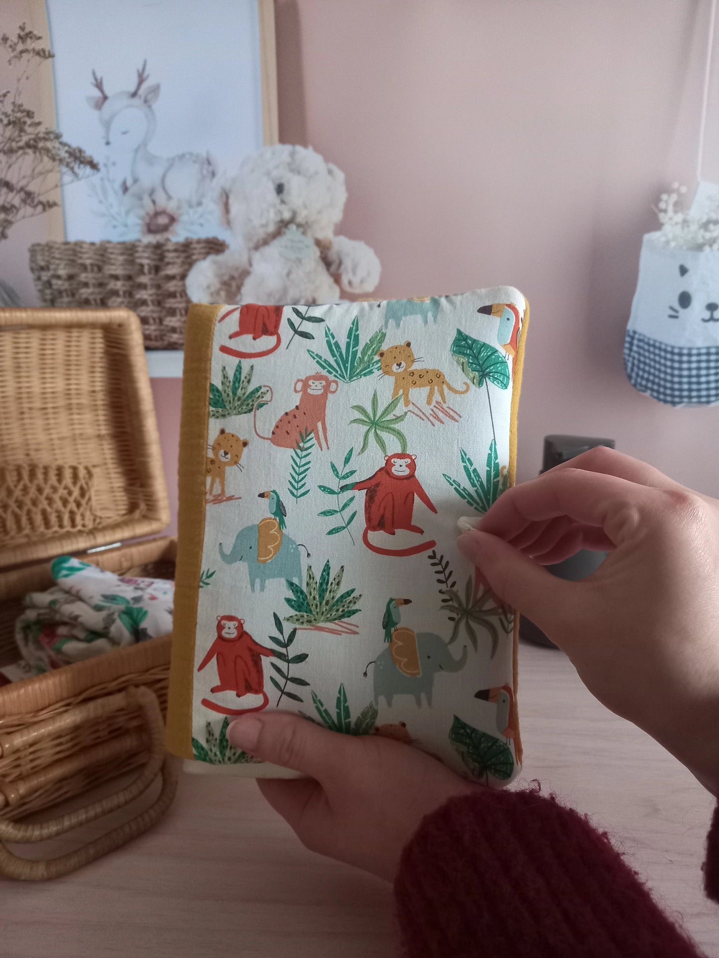 Couvre carnet de santé motif jungle tenu en main dans une chambre d'enfant