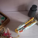 Couvre carnet de santé en tissu motif jungle avec liseré moutarde, fermé et posé sur un meuble