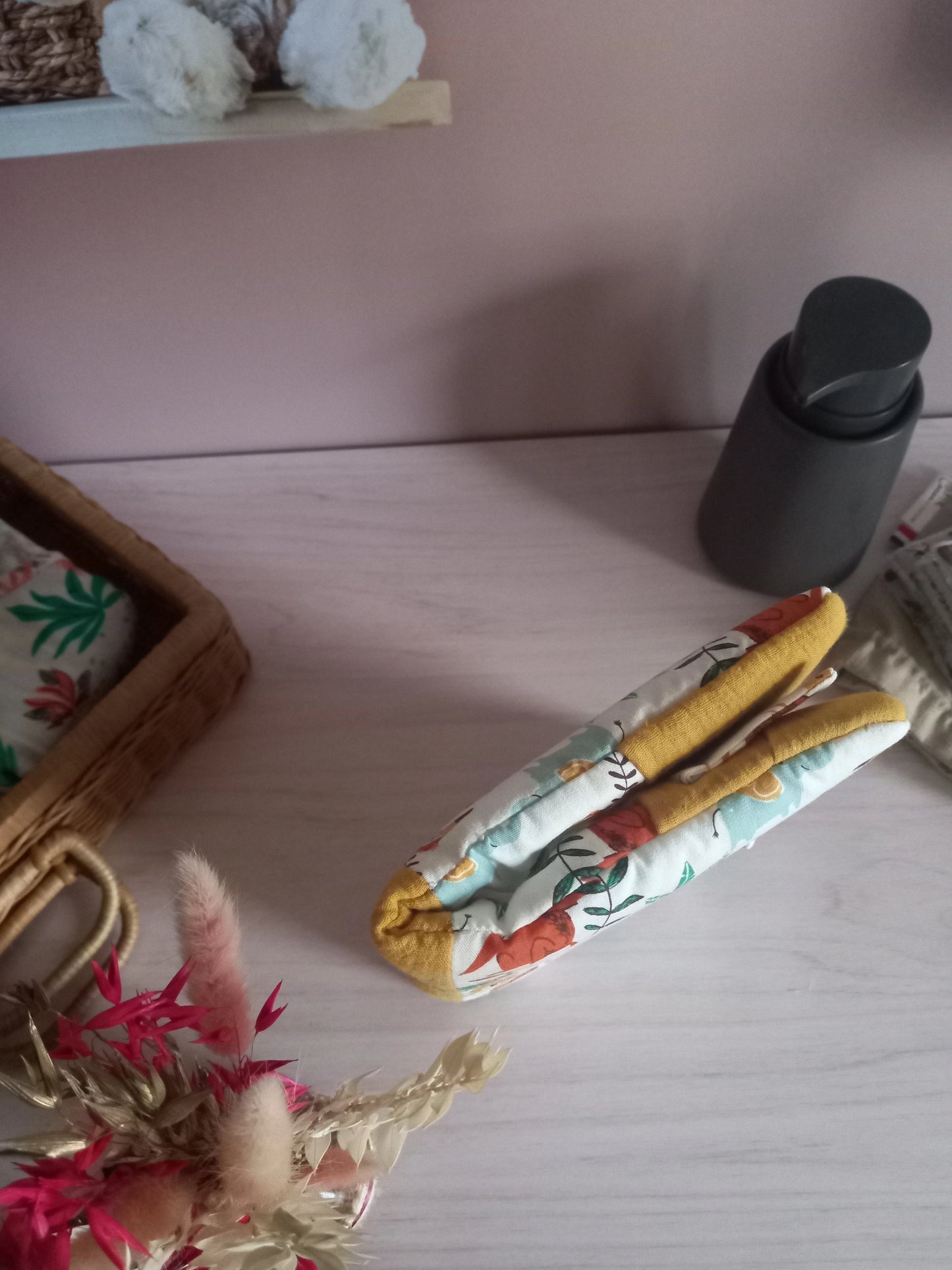 Couvre carnet de santé en tissu motif jungle avec liseré moutarde, fermé et posé sur un meuble