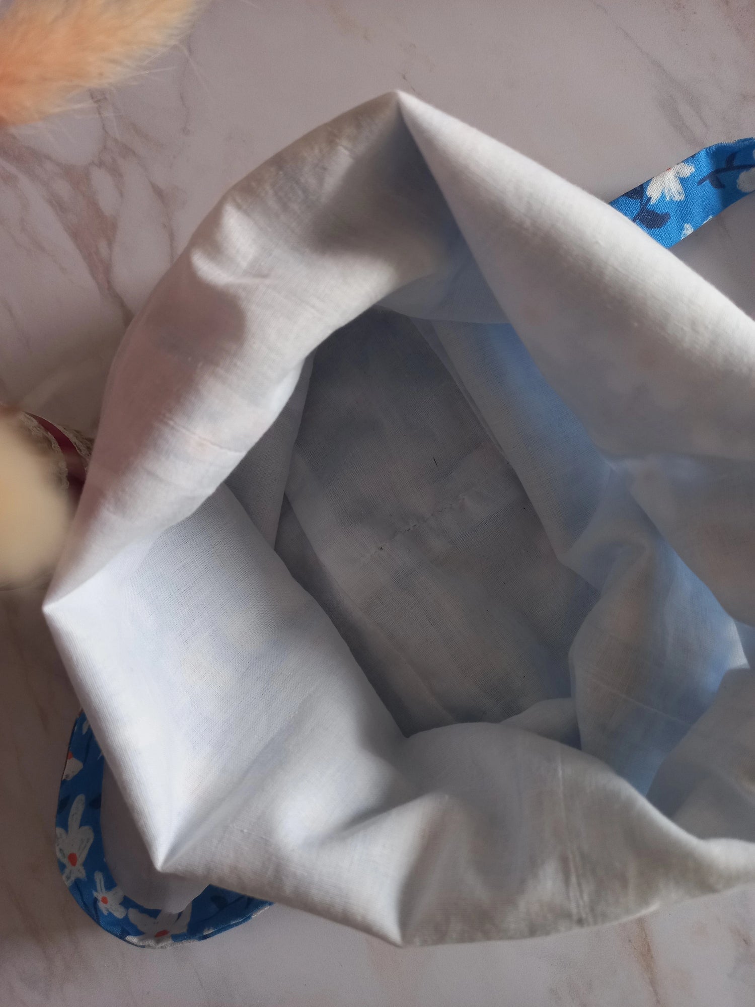 Vue de l'intérieur d'un pochon alimentaire en voile de coton blanc avec bordure motif fleuri bleu