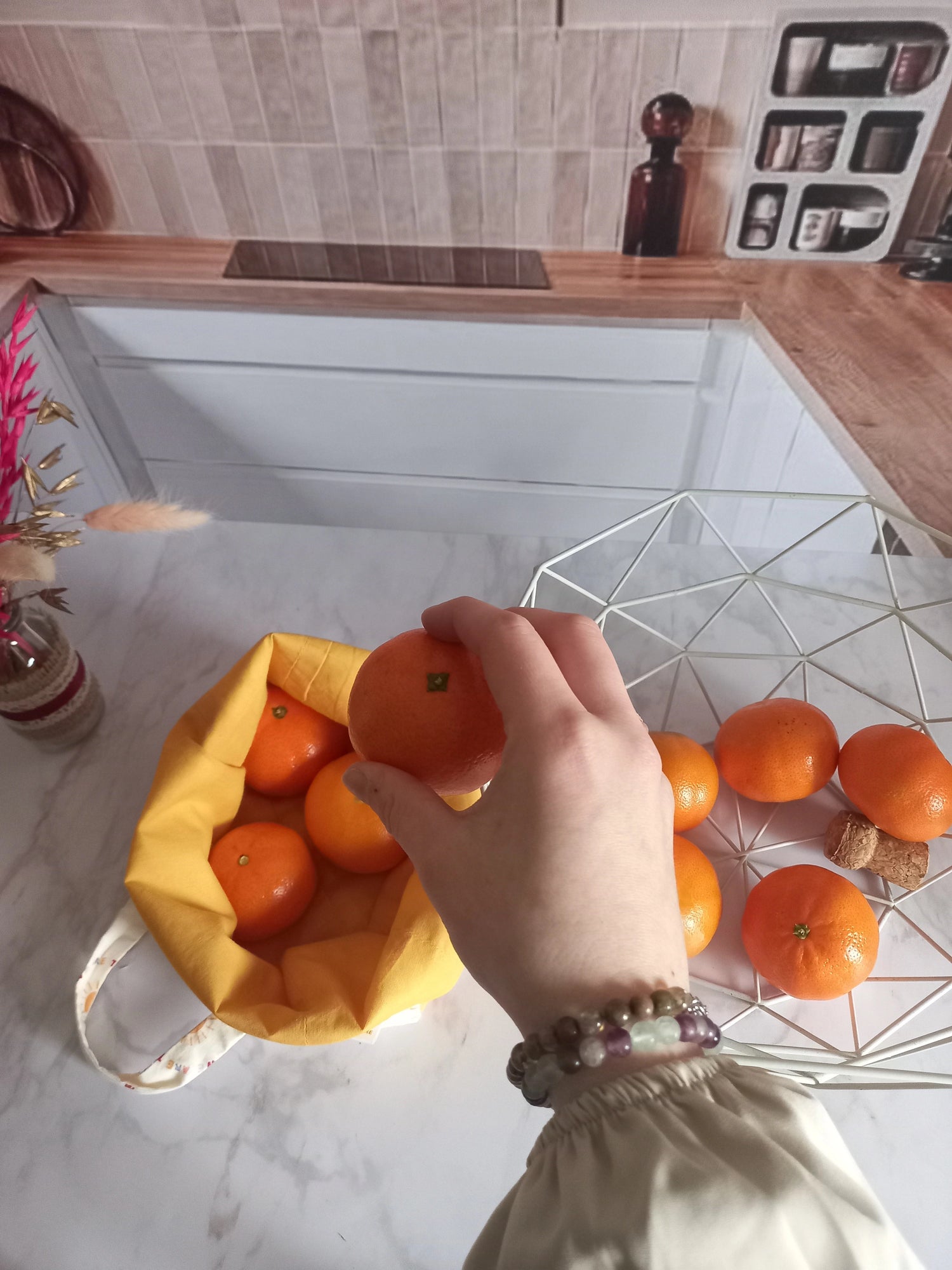 Vue de dessus d'une main tenant une orange au-dessus d'un pochon alimentaire collection Soleil rempli d'oranges