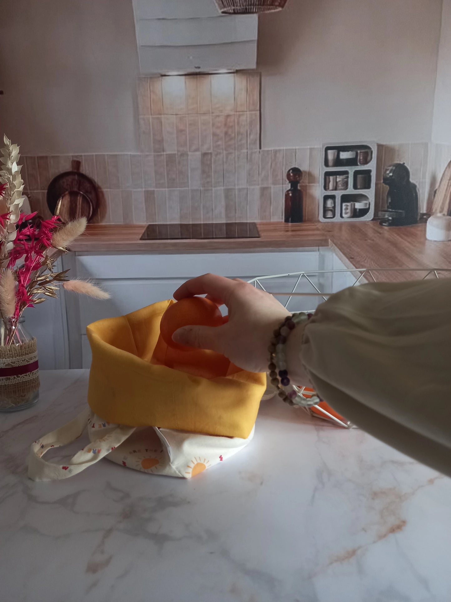 Main déposant une orange dans un pochon alimentaire collection Soleil dans une cuisine