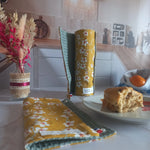 Rouleau essuie-tout lavable Cerisier ouvert et roulé dans une cuisine avec, à côté, des fleurs séchées et un gâteau