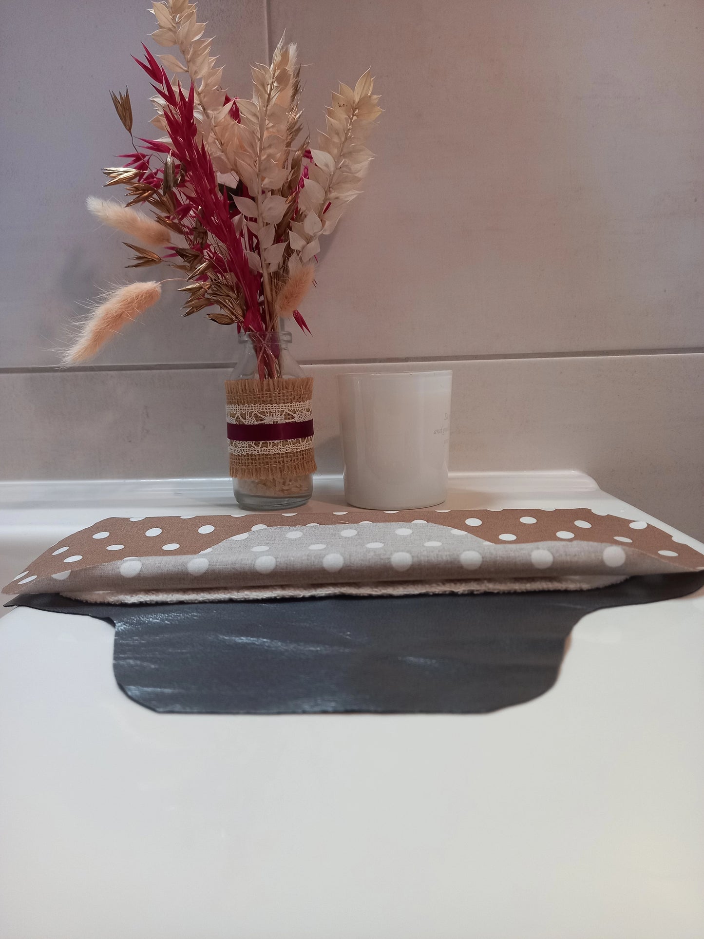 La serviette menstruelle lavable à pois est présentée en coupe, non cousue. On distingue le côté motif en coton, une épaisseur de tissu éponge absorbant et la face imperméable grise.